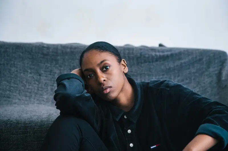 Woman sitting against a sofa with her head resting on her arm, reflecting on her own female sexual response