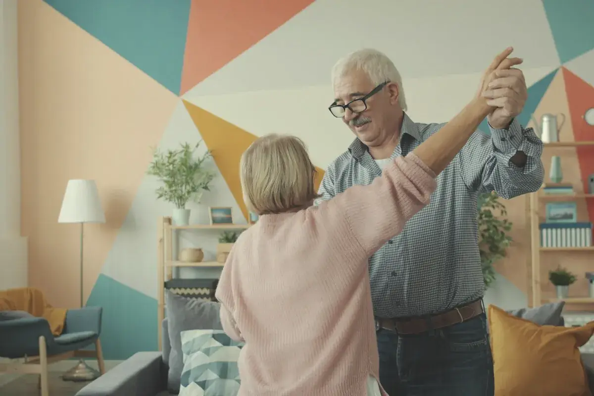 Elderly couple dancing happily in a colorful living room