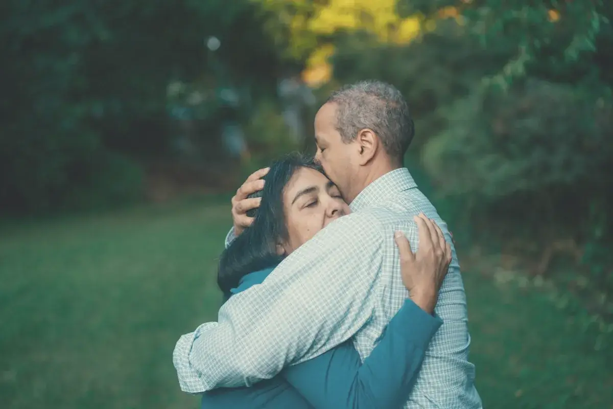 Man hugging woman near trees