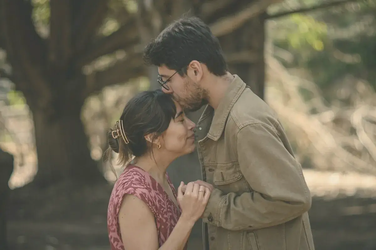 Man kisses woman's forehead in a tender moment outdoors