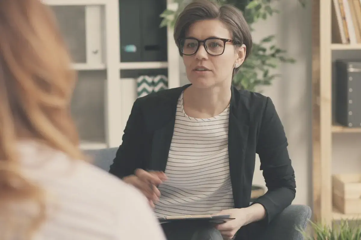 A woman sitting on a couch talking to another woman