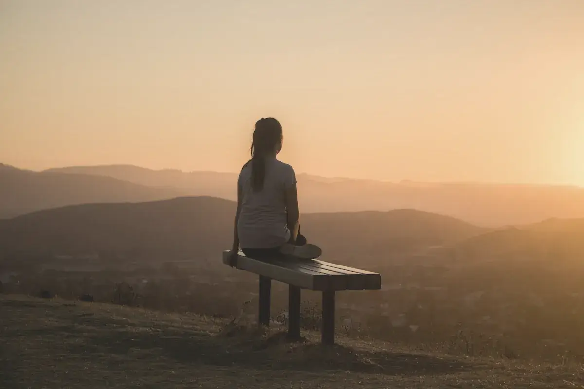 Woman sitting on bench over viewing mountain