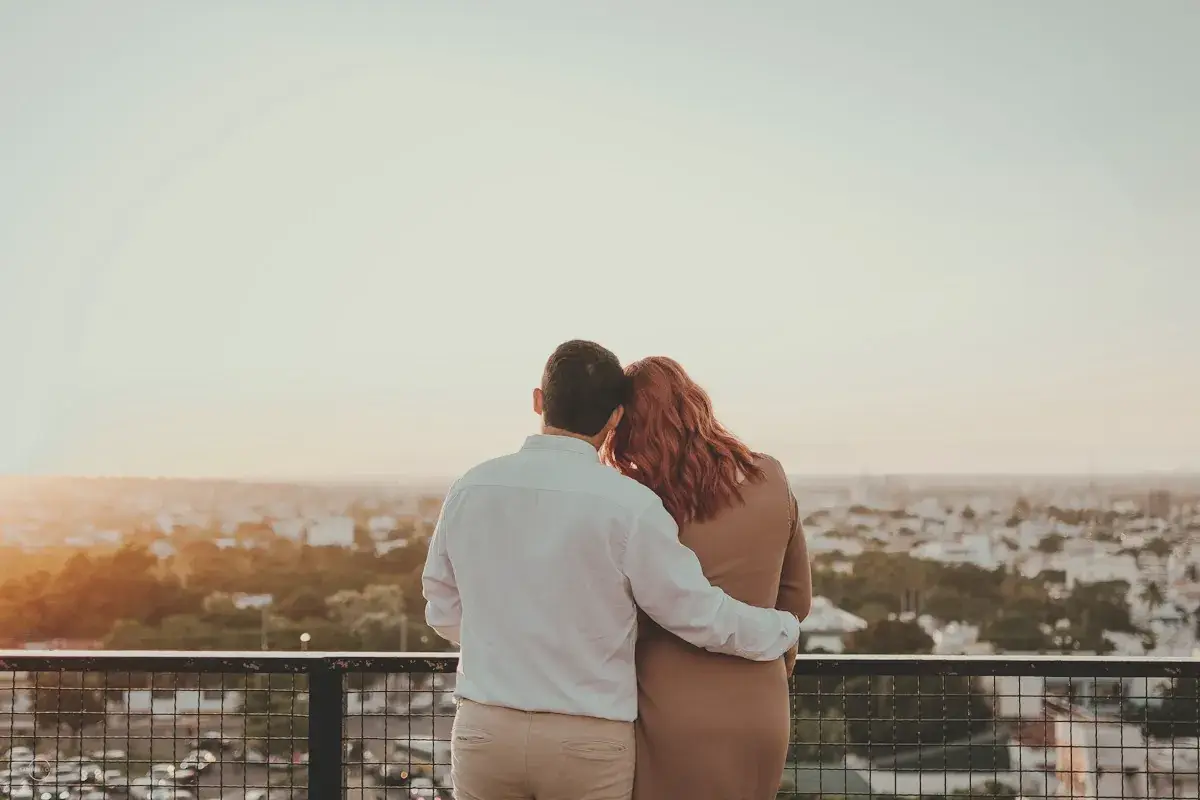Couple embracing and watching city skyline at sunset