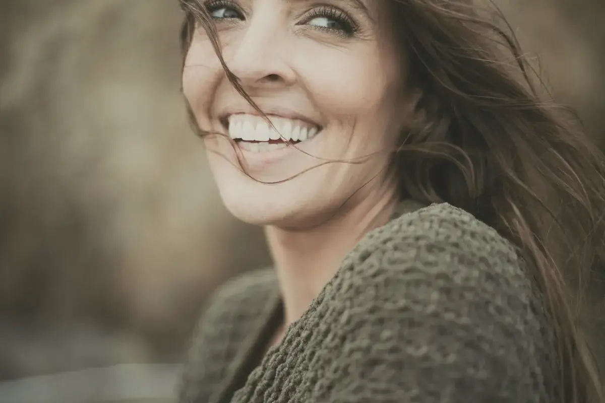 Woman in her forties smiling with her hair blowing across her face