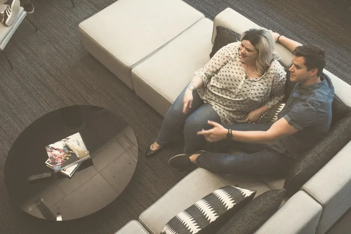 Man and woman sitting beside each other on gray padded sectional sofa