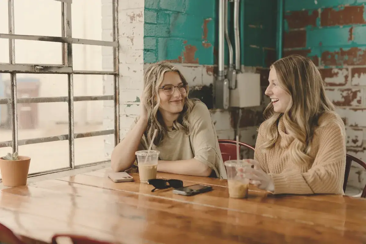 A couple of women sitting at a wooden table