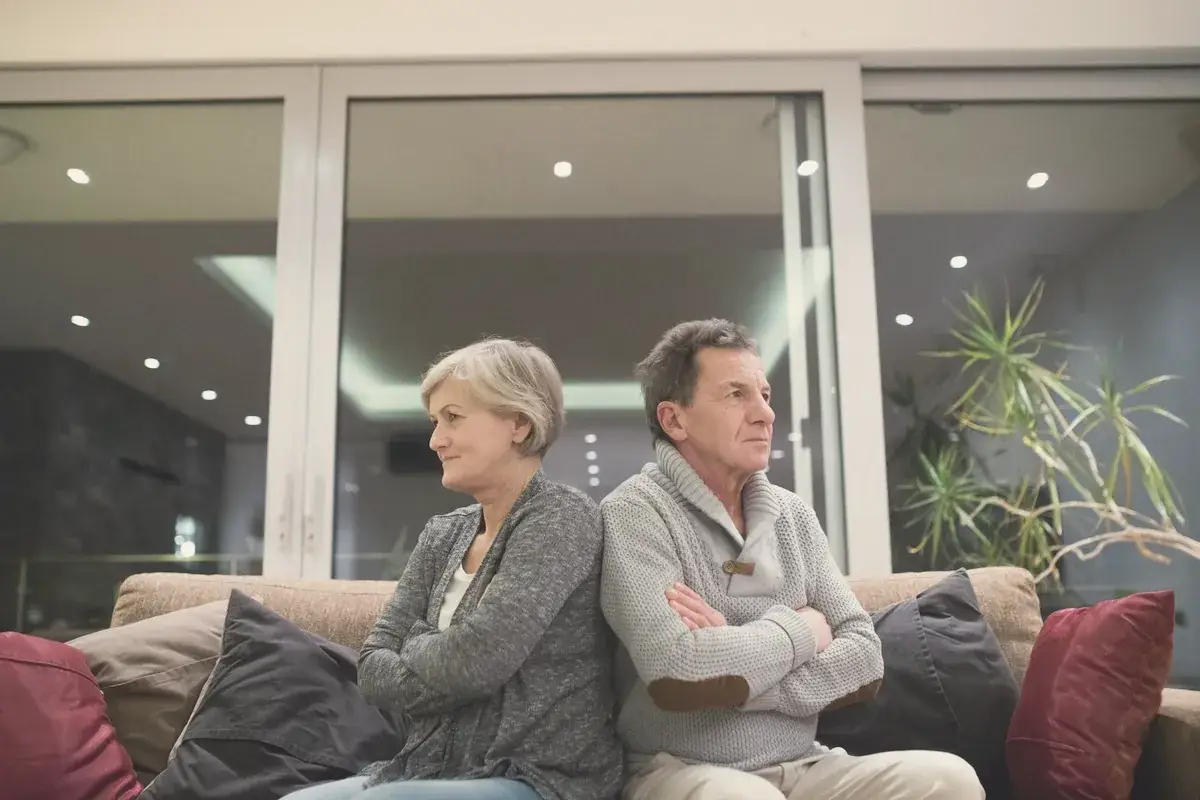 Older couple sitting on a couch with their arms crossed