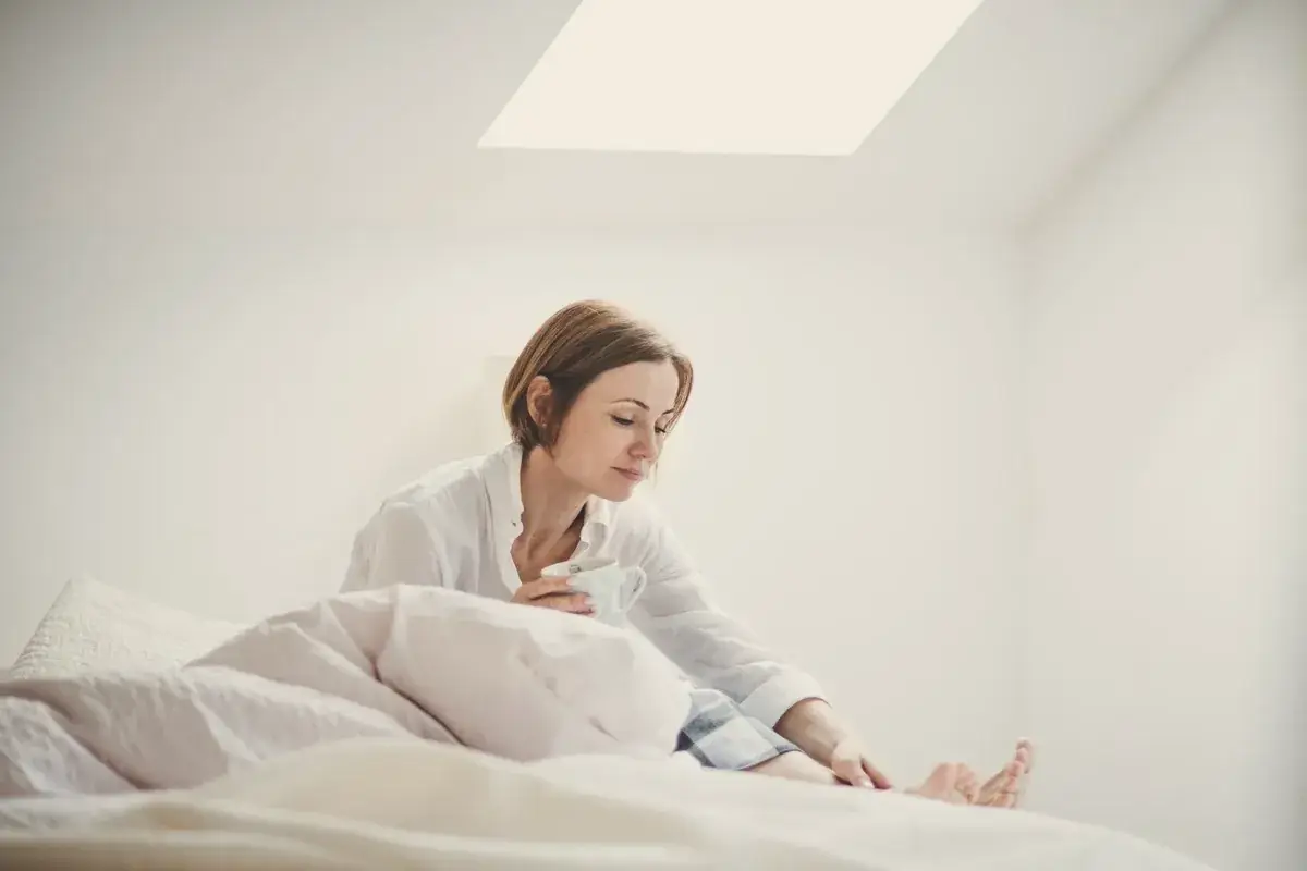 Woman sitting on her bed in the morning, looking down
