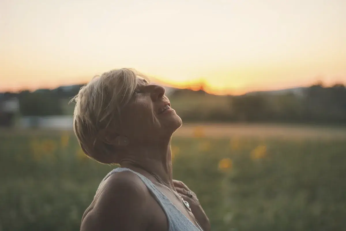 Woman in white tank top looking at the sunset